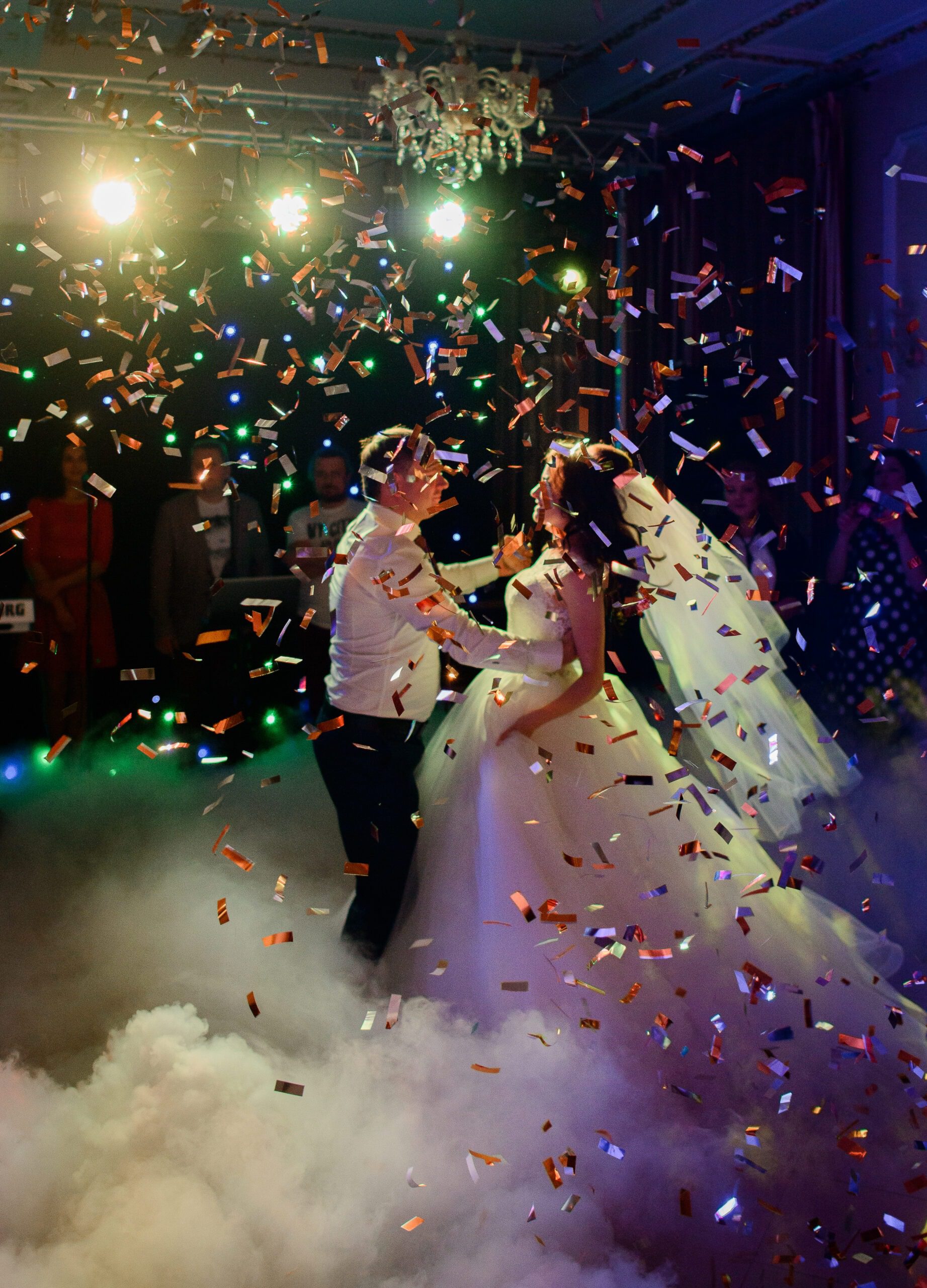 Confetti fall on wedding couple whirling in the smoke